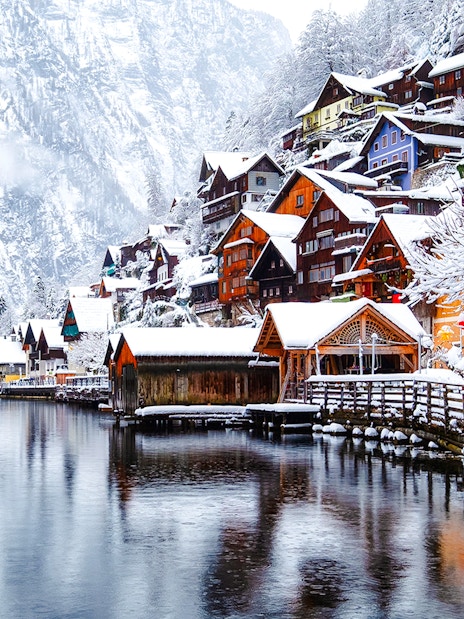 Hallstatt village in Austria covered in snow during winter, with colorful houses by the lake.