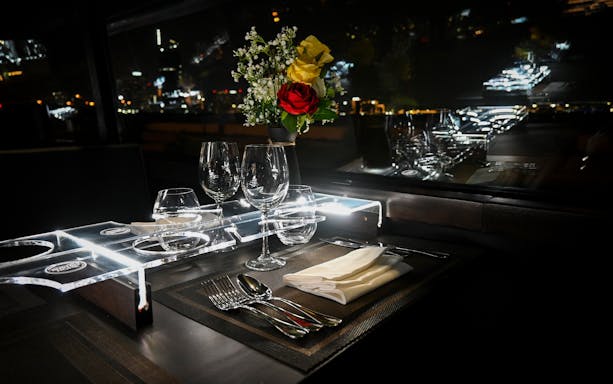 Dining setup inside Bustronome bus, Dubai, with glassware and flowers.