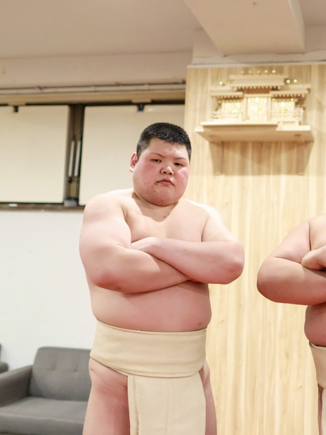 Sumo wrestlers posing after a match in a traditional Japanese setting.