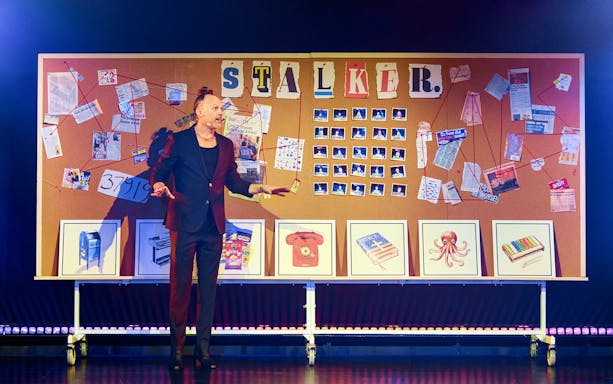 Man presenting in front of a bulletin board with "Stalker" and various photos and notes.