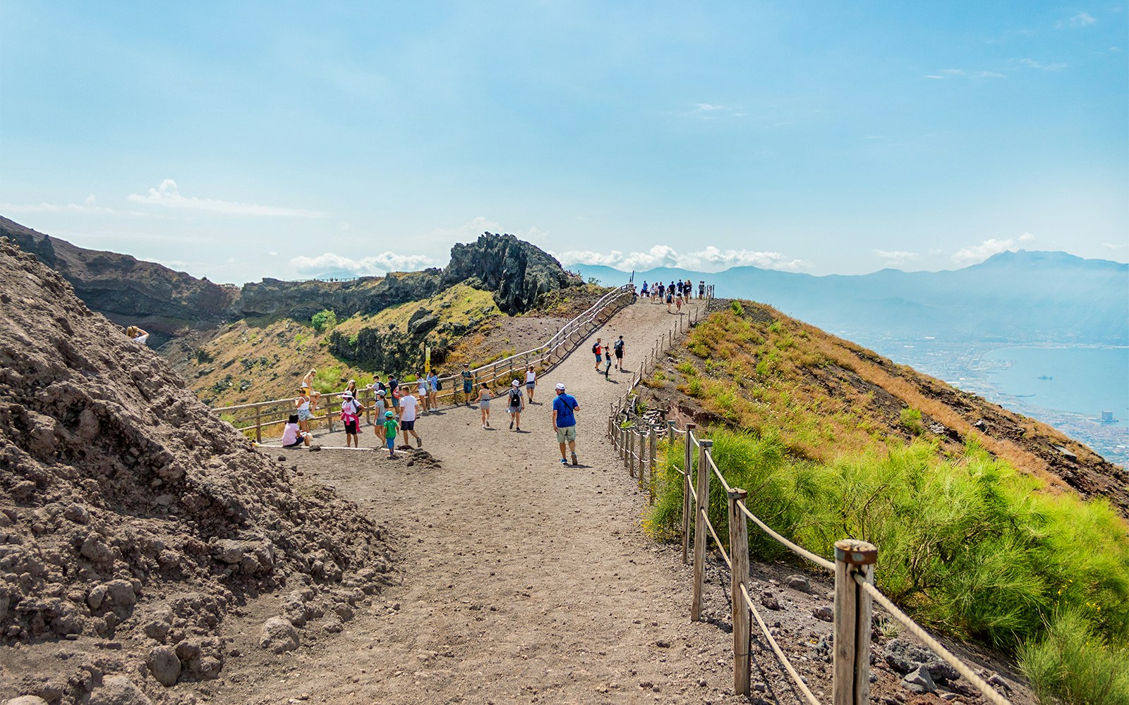 Hikers ascending Mount Vesuvius with panoramic views of the Bay of Naples, Italy.