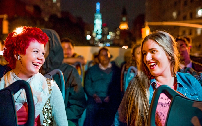 Two women enjoying a Dublin night tour on an open-top bus.