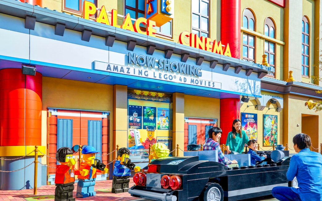 Family enjoying Lego car ride at Legoland Japan's Palace Cinema entrance.