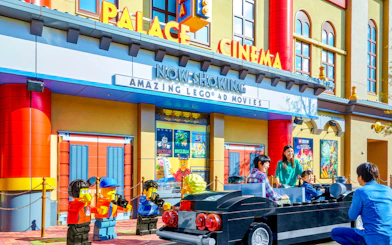 Family enjoying Lego car ride at Legoland Japan's Palace Cinema entrance.