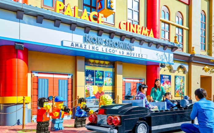 Family enjoying Lego car ride at Legoland Japan's Palace Cinema entrance.