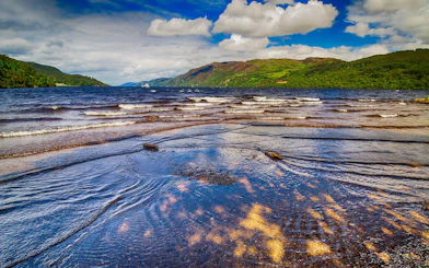 Loch Ness shoreline with distant hills and a boat on the water.