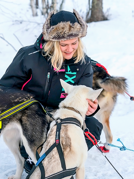 Husky sledding guide with dogs in snowy Rovaniemi forest.