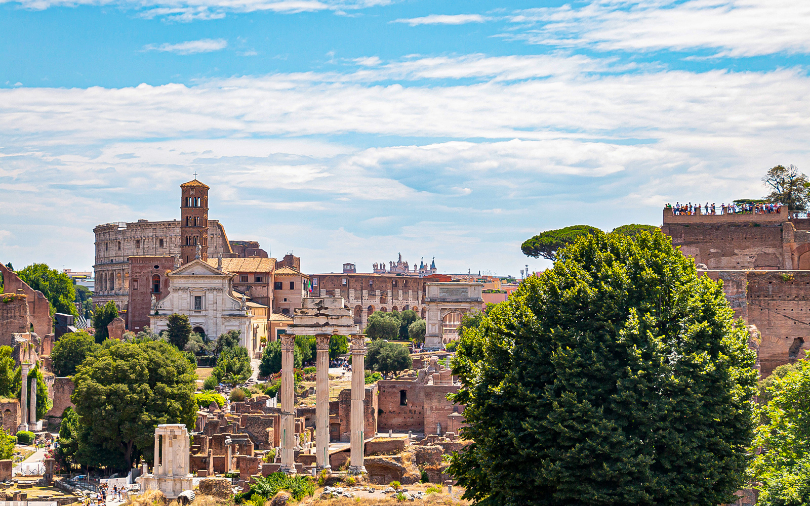 Colosseum and Roman Forum ruins in Rome, Italy, viewed from a distance.