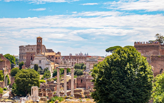 Colosseum and Roman Forum ruins in Rome, Italy, viewed from a distance.