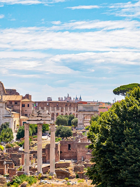 Colosseum and Roman Forum ruins in Rome, Italy, viewed from a distance.
