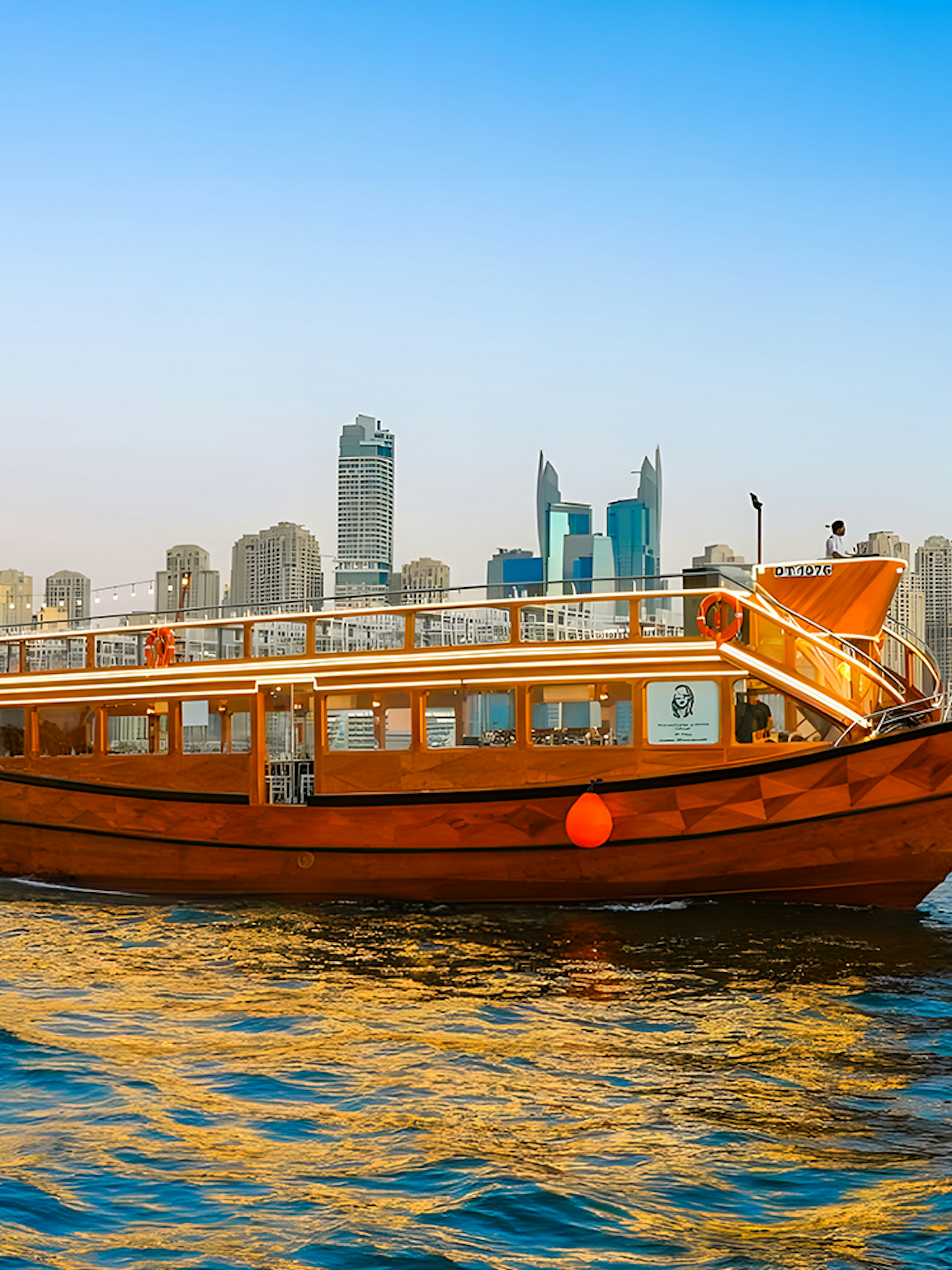Dhow boat cruising in Dubai Marina with city skyline in the background.