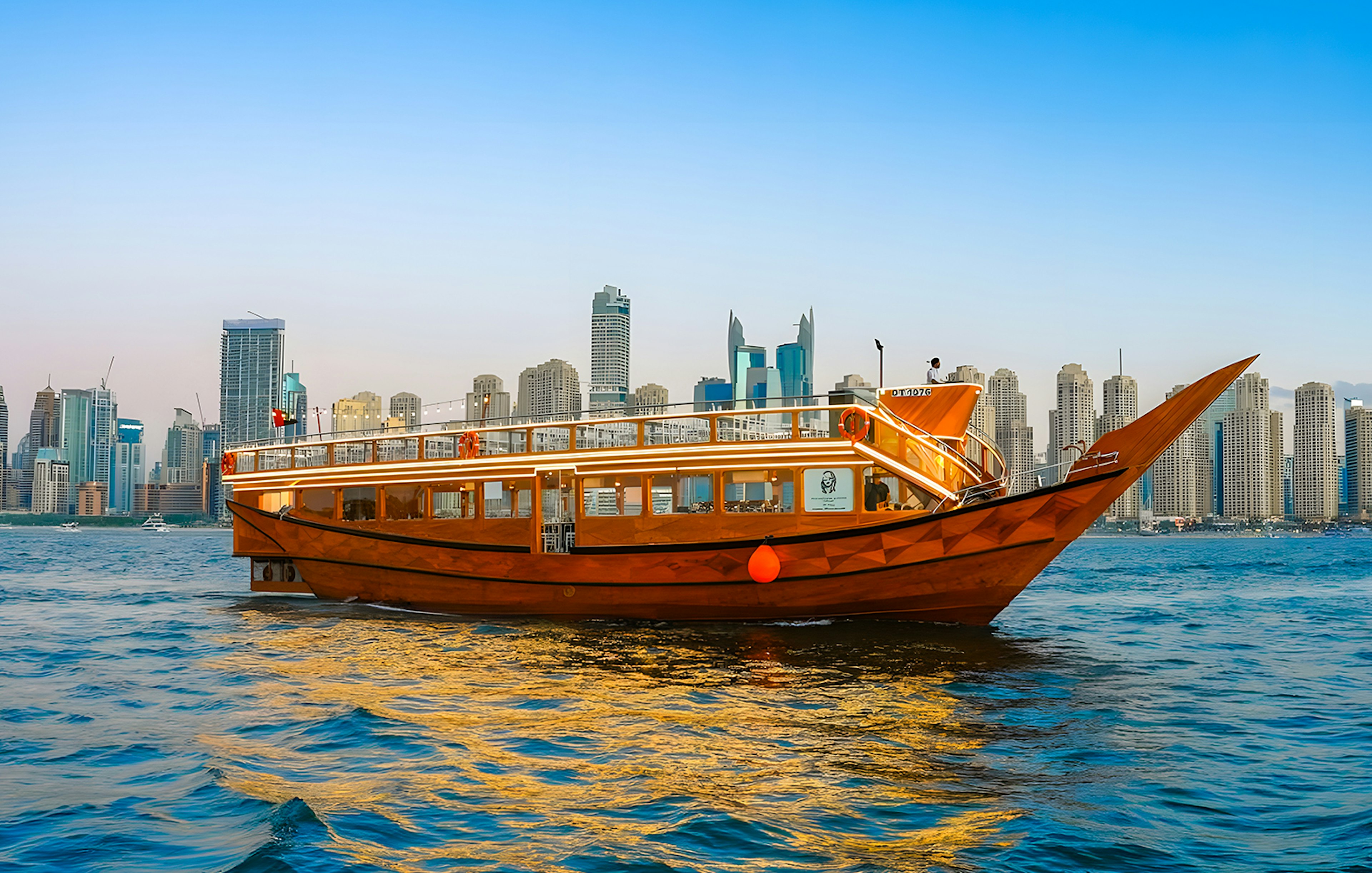 Dhow boat cruising in Dubai Marina with city skyline in the background.