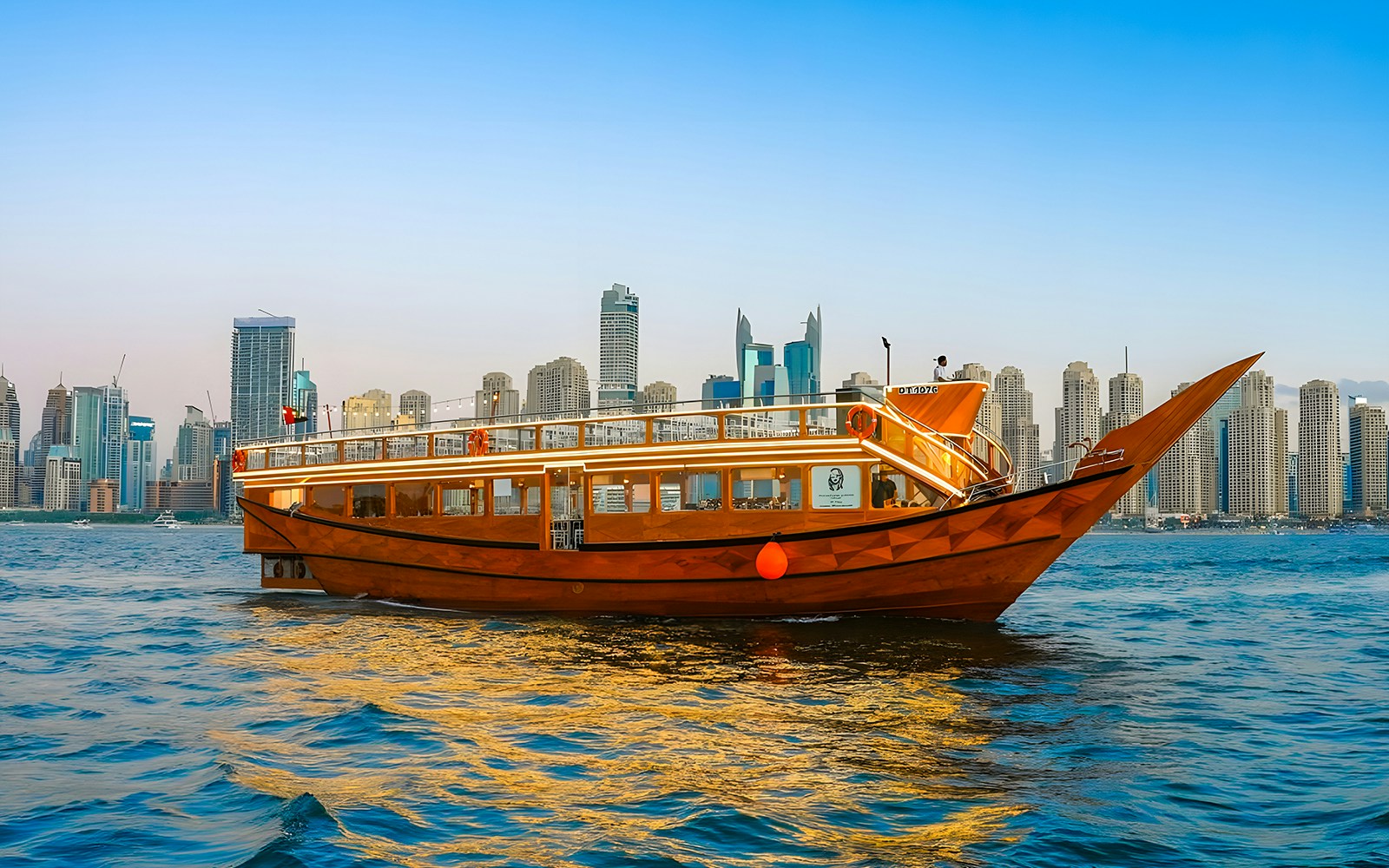 Dhow boat cruising in Dubai Marina with city skyline in the background.