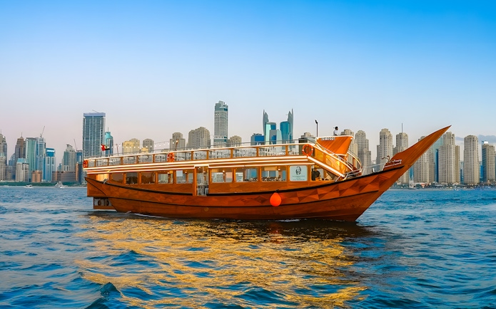 Dhow boat cruising in Dubai Marina with city skyline in the background.