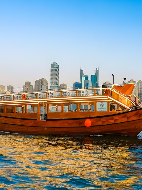 Dhow boat cruising in Dubai Marina with city skyline in the background.