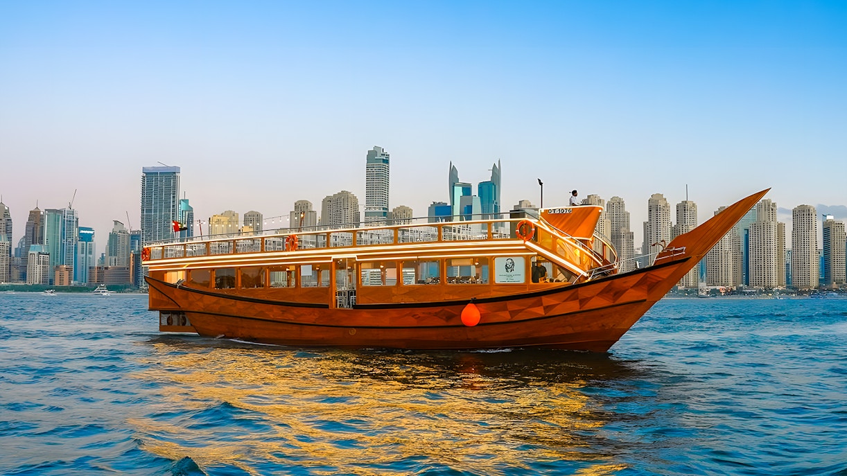 Dhow boat cruising in Dubai Marina with city skyline in the background.
