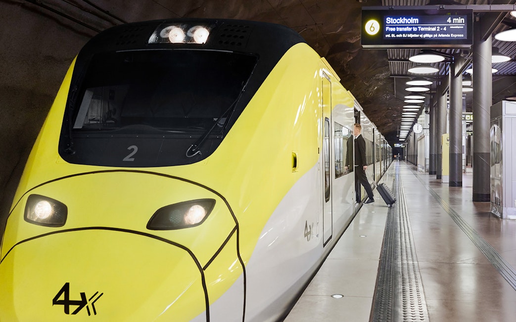 Arlanda Express train at Stockholm Arlanda Airport platform with passenger boarding.