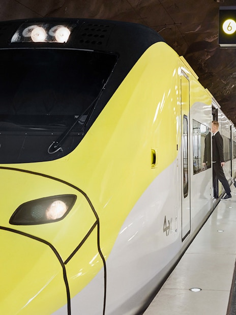 Arlanda Express train at Stockholm Arlanda Airport platform with passenger boarding.