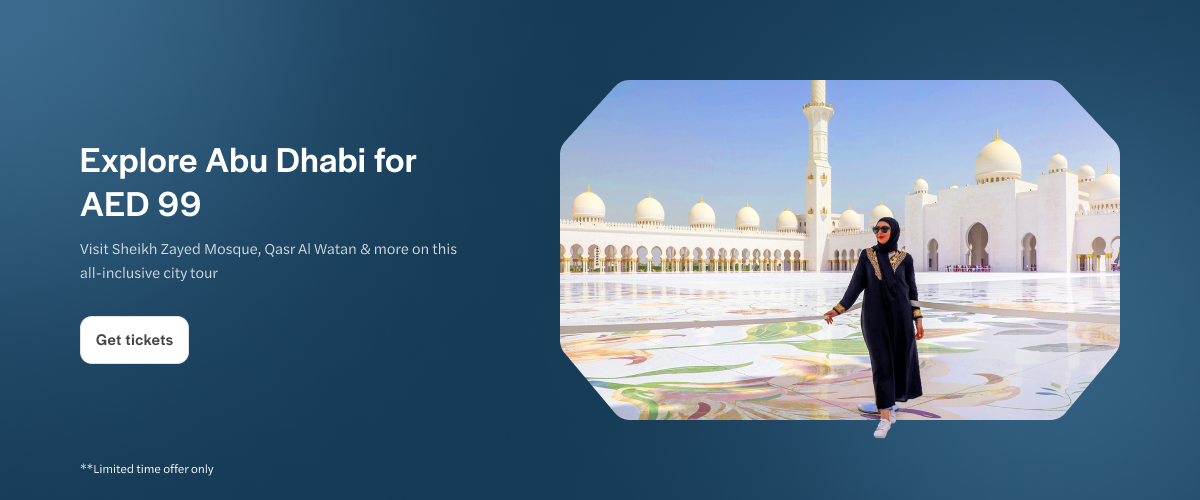 Sheikh Zayed Mosque in Abu Dhabi with a visitor walking on the marble courtyard.