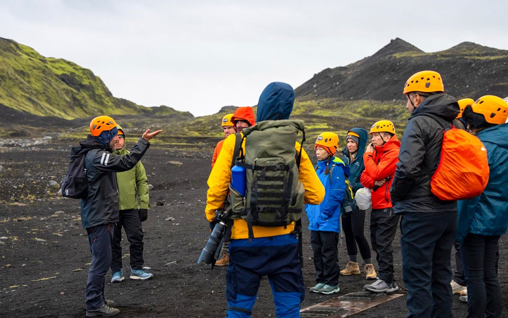 Tour guide assisting group during Katla Ice Cave hike in Iceland.