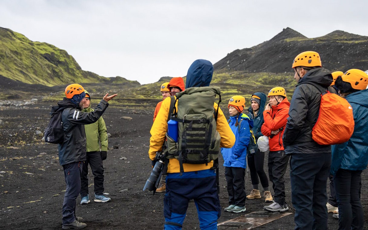Tour guide assisting group during Katla Ice Cave hike in Iceland.