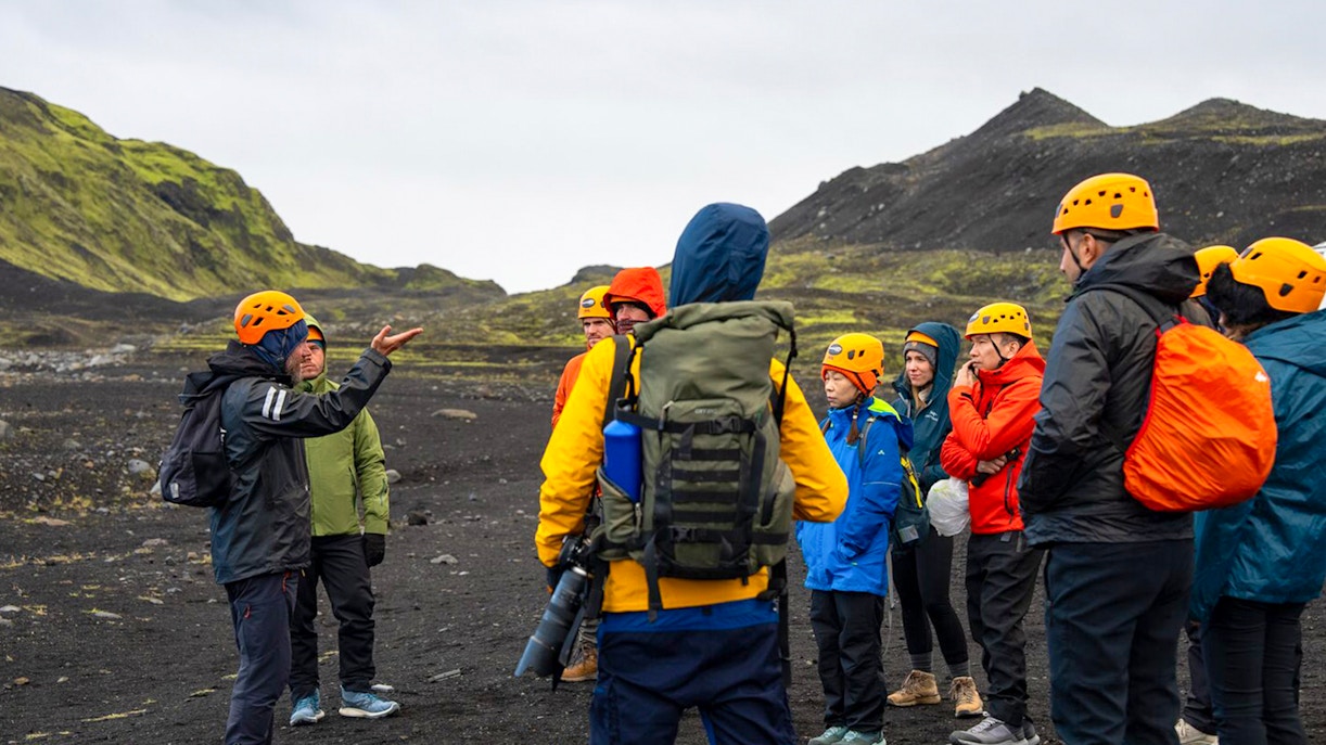 Tour guide assisting group during Katla Ice Cave hike in Iceland.