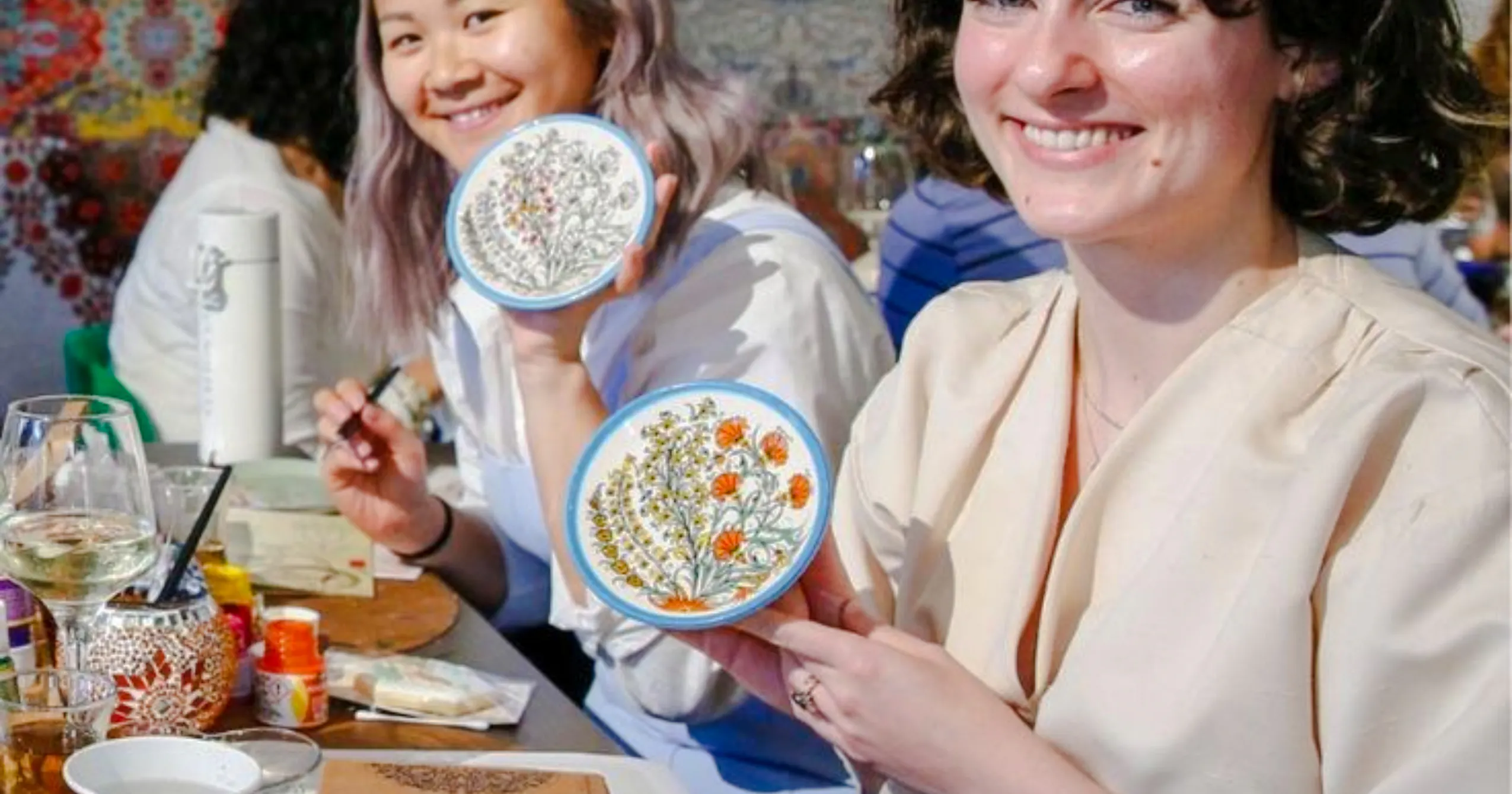 Participants displaying painted ceramic plates at a Moroccan art workshop in Marrakech Medina.