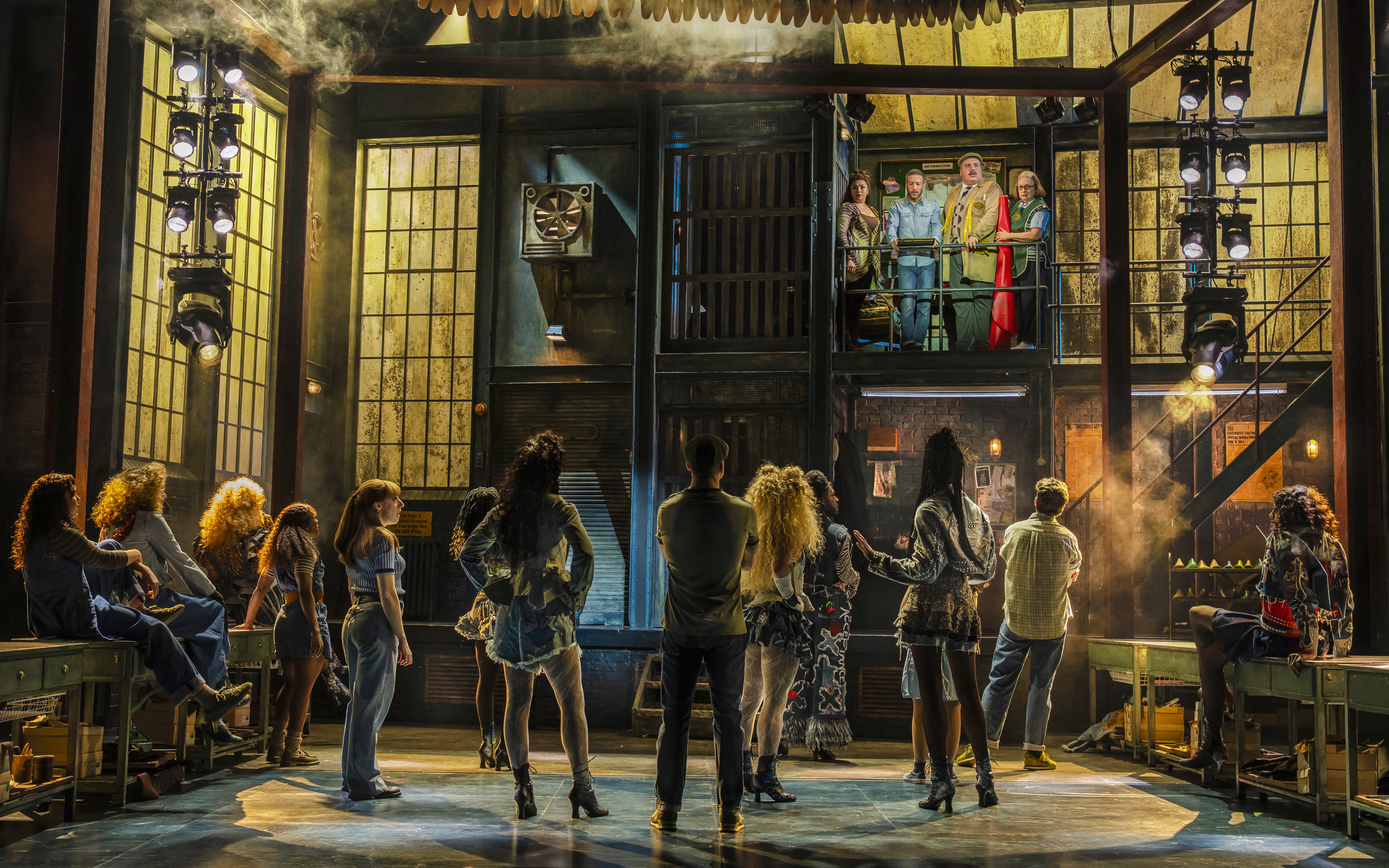 Stage scene from "Kinky Boots" with cast members in a factory setting.