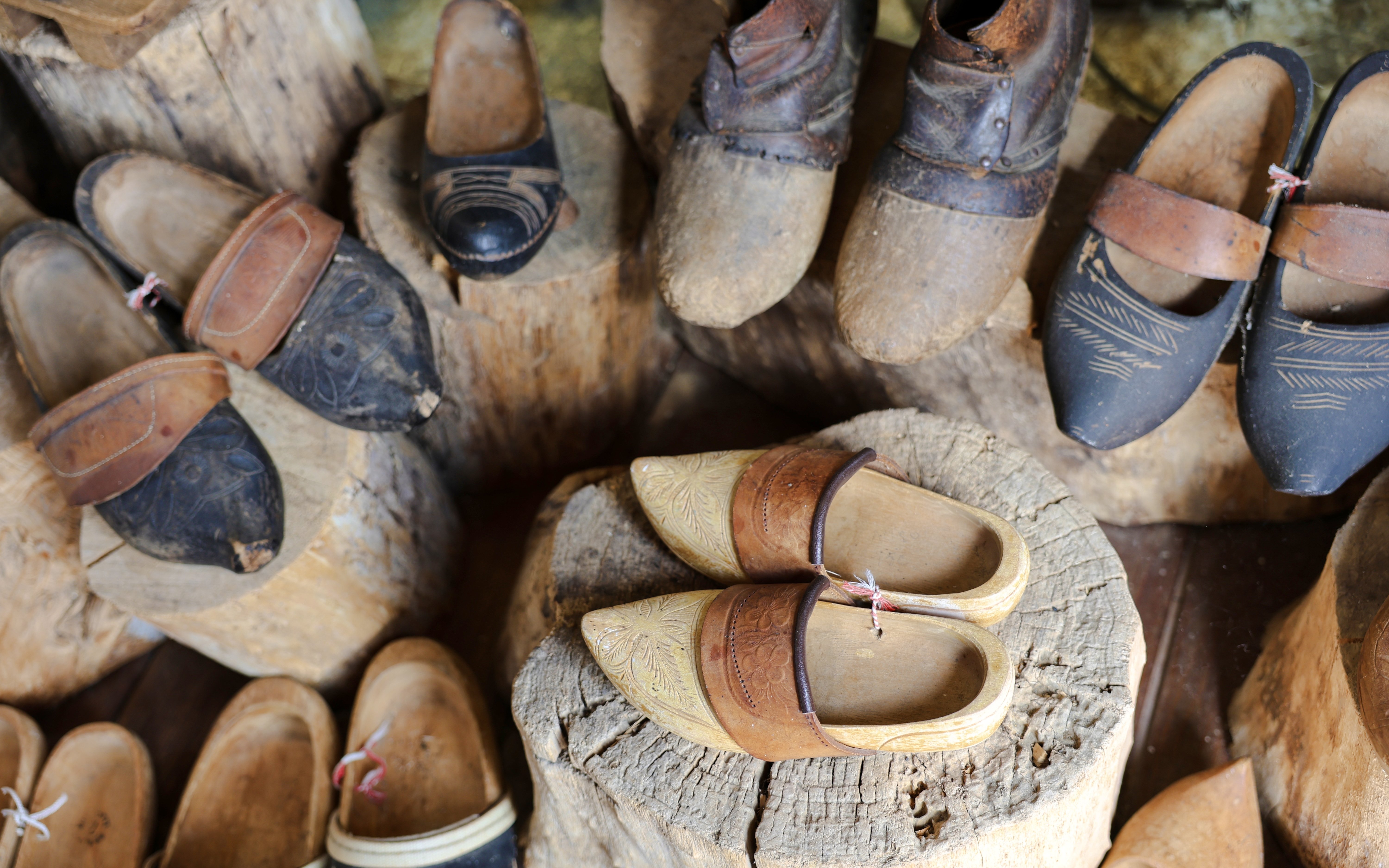Traditional wooden clogs displayed on logs at a clog-making workshop.
