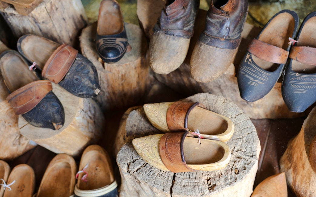 Traditional wooden clogs displayed on logs at a clog-making workshop.