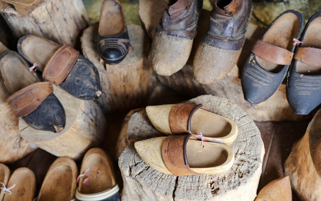 Traditional wooden clogs displayed on logs at a clog-making workshop.