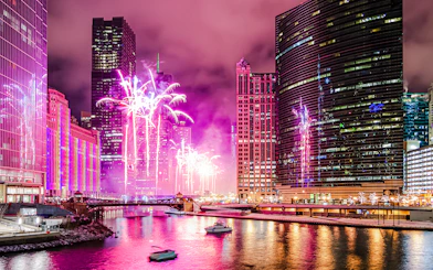 Fireworks display over Wolf Point in Chicago, USA, with city skyline and river.