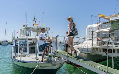 Tourist boarding catamaran boat at marina with colorful flags.