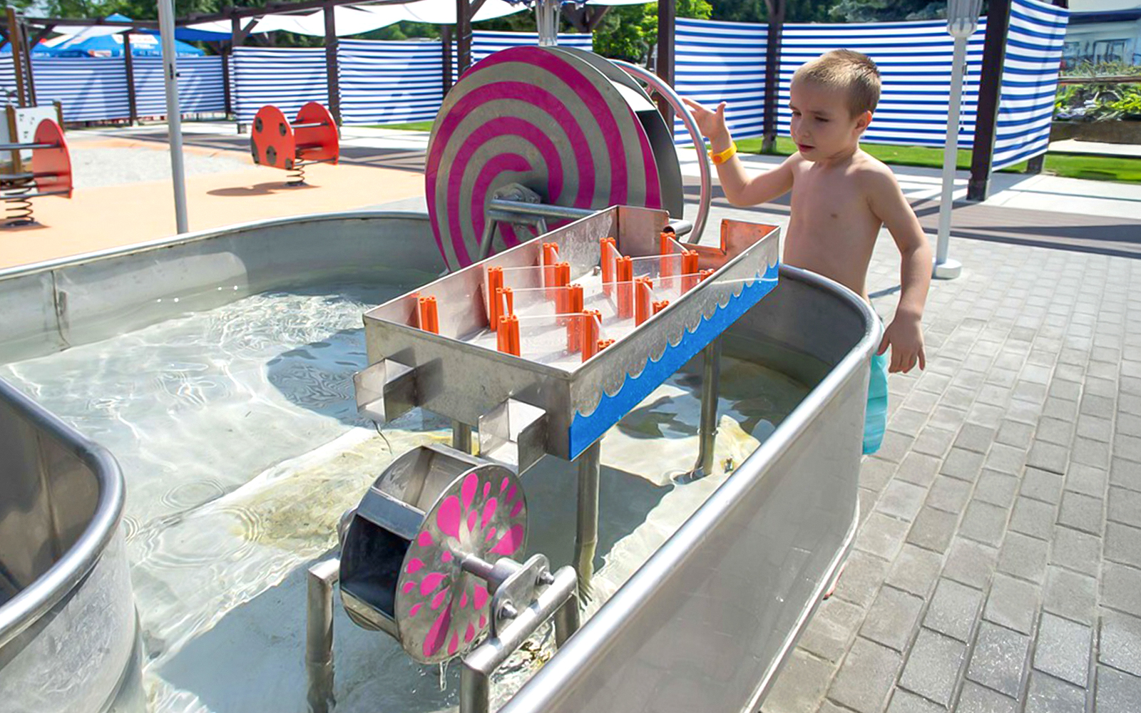 Child engaging with water play equipment at Palatinus Spa playground, Budapest.