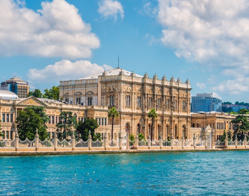 Dolmabahce Palace exterior with tourists on a guided tour in Istanbul, showcasing ornate architecture.