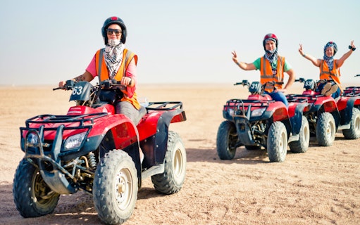 Group riding quad bikes in desert landscape.