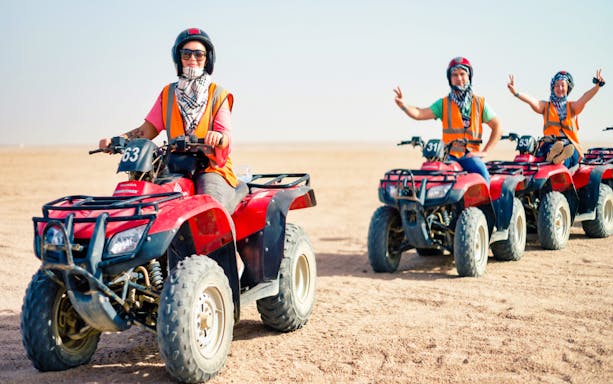 Group riding quad bikes in desert landscape.