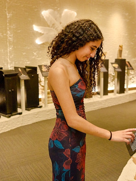 Visitor reads plaque in front of golden artifacts at Tomb of the Pharaoh exhibit.