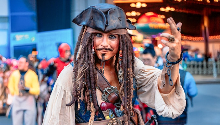 Jack Sparrow cosplayer at Walt Disney World, Orlando, posing with a crowd in the background.