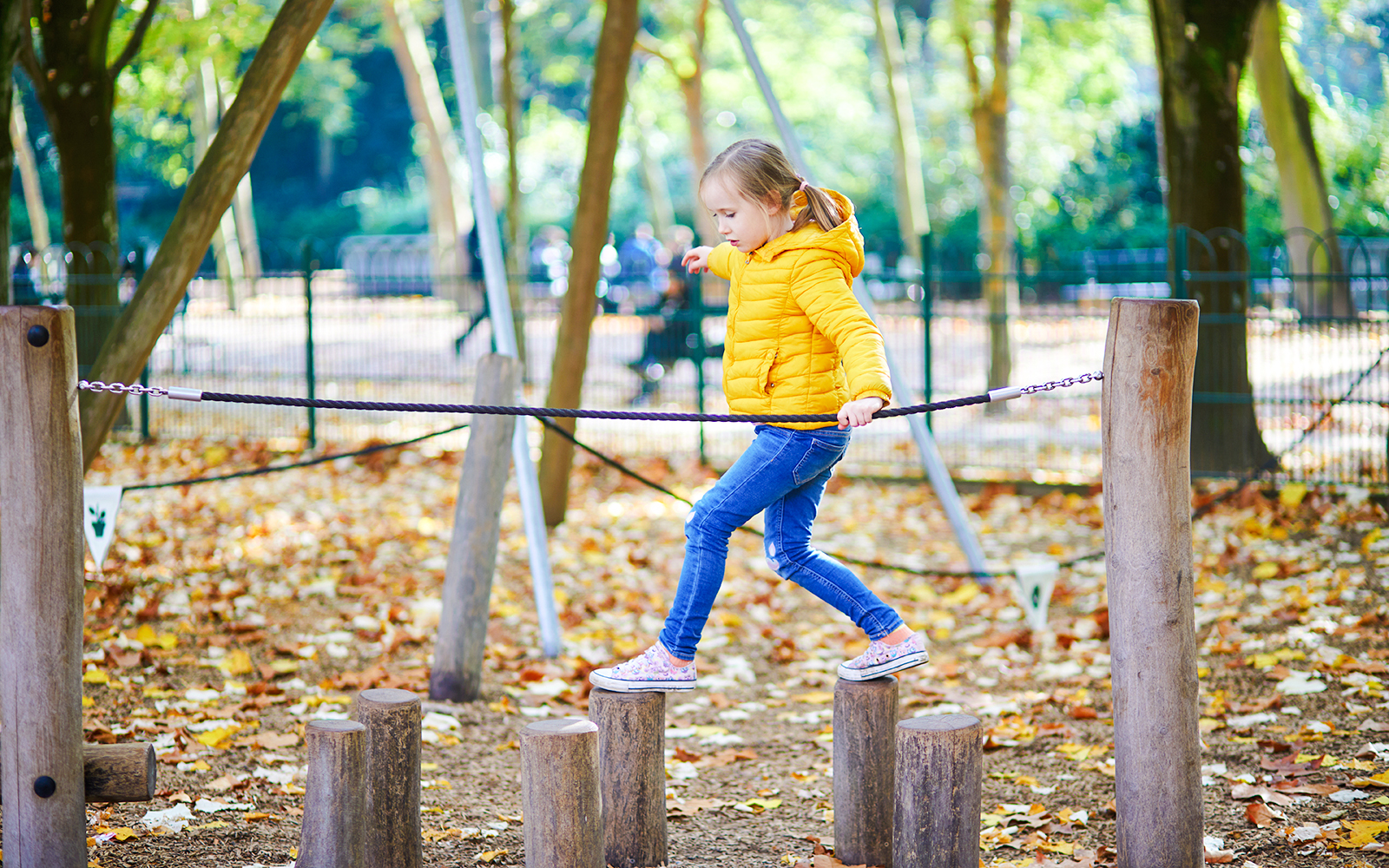 Child balancing on wooden stepping stones at Square Paul Séramy, Paris.