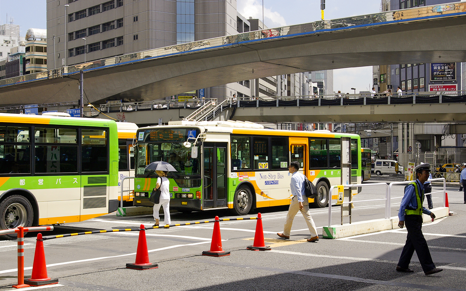 Tokyo city buses at a busy intersection, part of the Greater Tokyo Pass experience.
