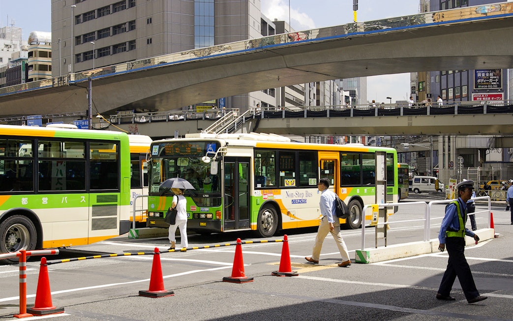 Tokyo city buses at a busy intersection, part of the Greater Tokyo Pass experience.