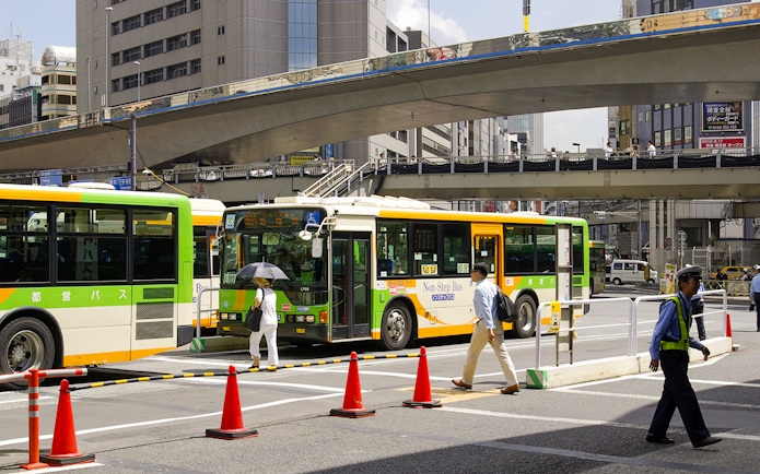 Tokyo city buses at a busy intersection, part of the Greater Tokyo Pass experience.