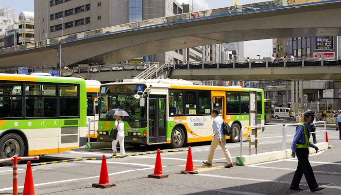 Tokyo city buses at a busy intersection, part of the Greater Tokyo Pass experience.