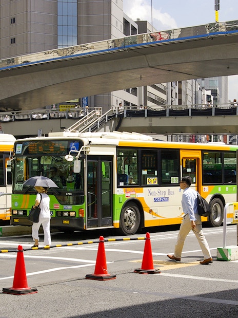 Tokyo city buses at a busy intersection, part of the Greater Tokyo Pass experience.