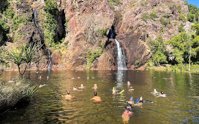 Visitors swimming near a waterfall in Litchfield National Park, Australia.