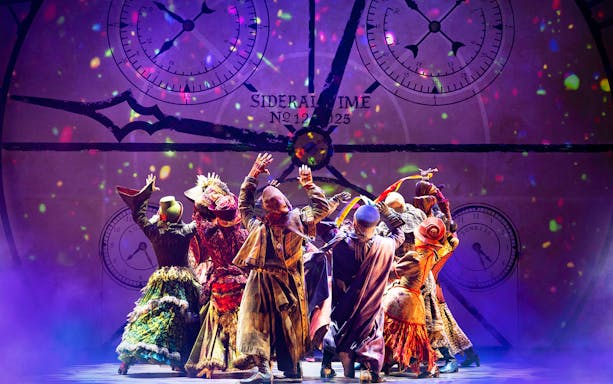 Performers in colorful costumes on stage during a Wicked musical scene.