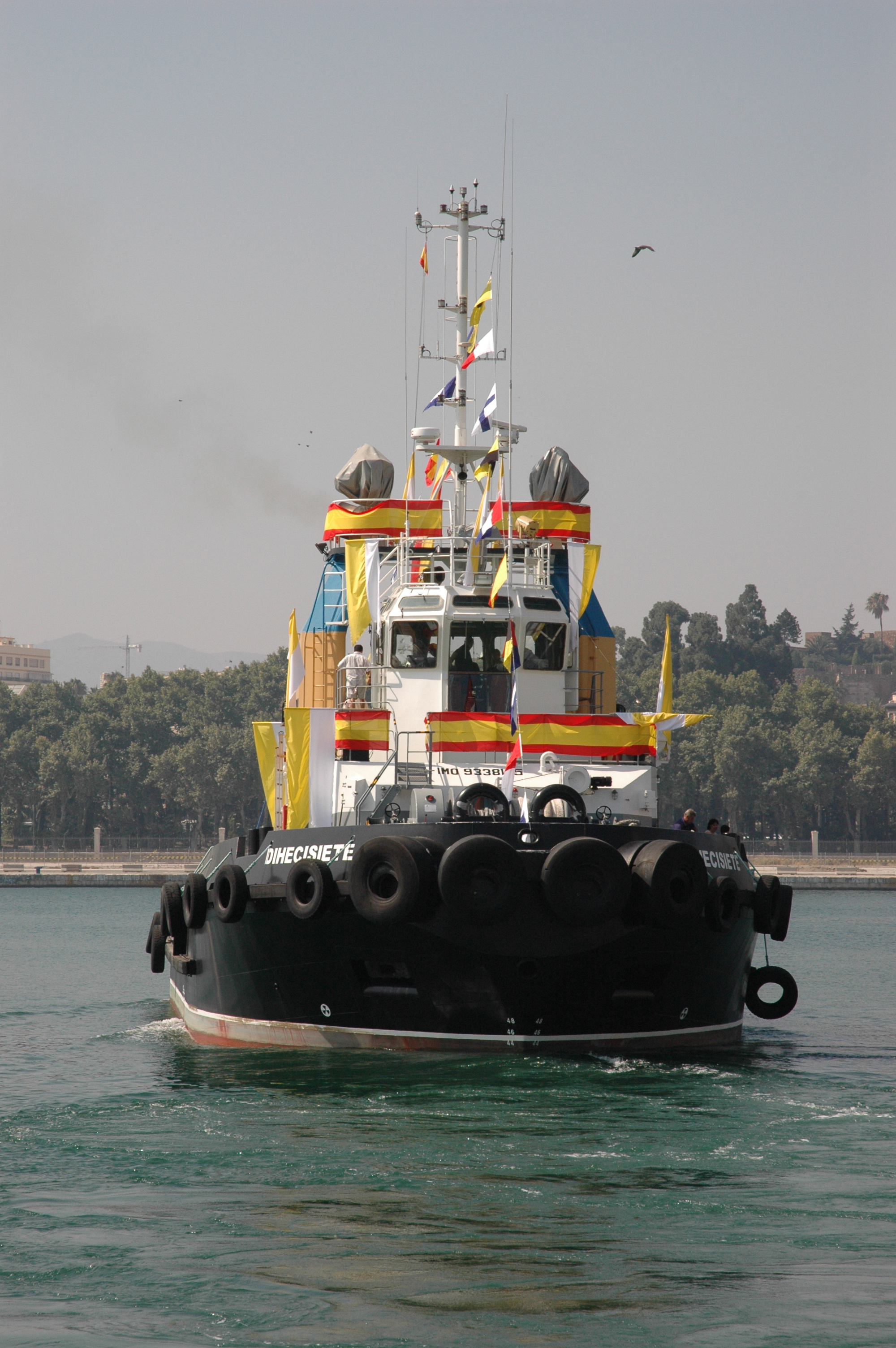 Decorated tugboat for Fiesta del Carmen in harbor, flags and banners displayed.