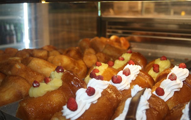 Naples street food pastries with cream and berries in a display case.