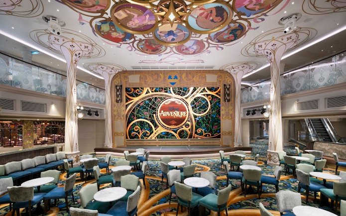 Disney Cruise Line Town Square with ornate stage and colorful seating area.